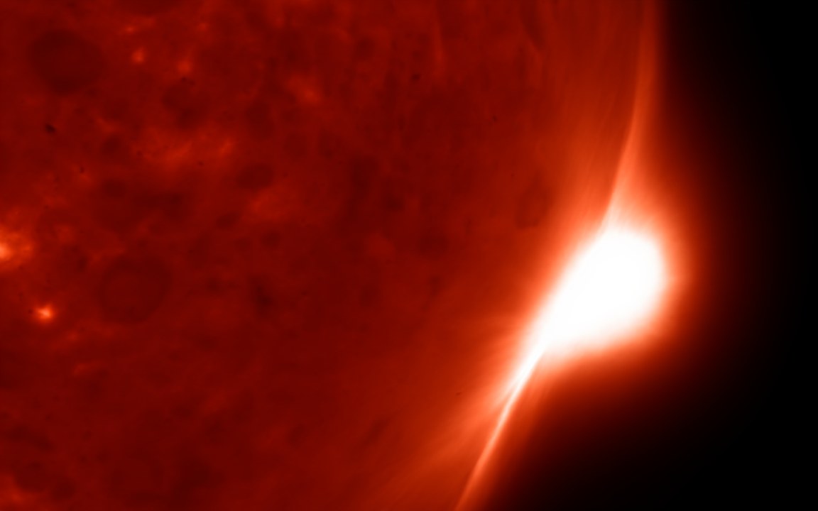 The mottled, deep red surface of a small star seen up close, with dark spots and a brilliant white flare bursting from its edge, an impression of Proxima Centauri during one of its flares.