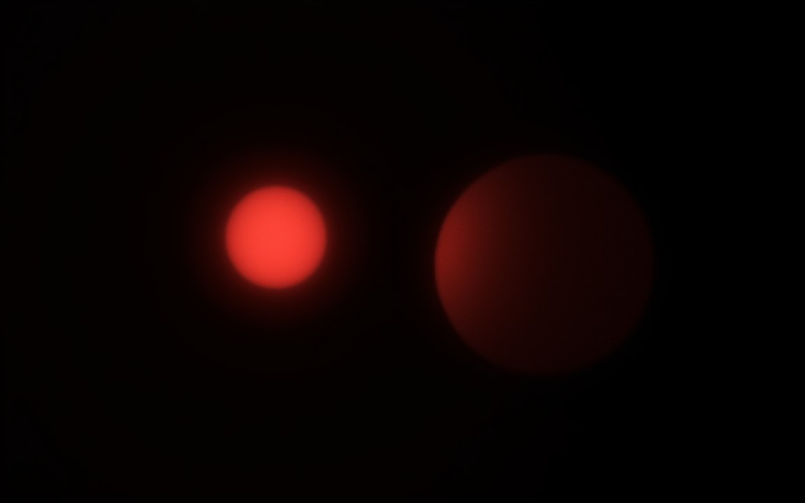 A small, glowing red star beside a dark planet of about the same size, an impression of the smallest known star compared with a gas giant.